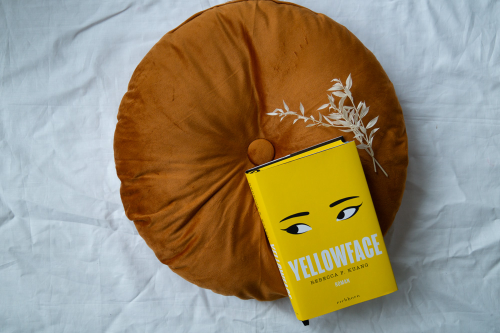 Das Buch von Rebecca F. Kuang - Yellowface ist auf einem braunen Kissen drapiert.